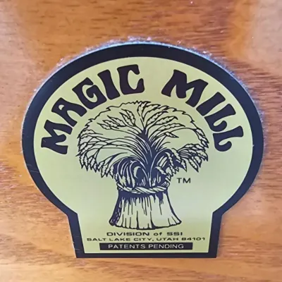 Magic Mill brand label on a wooden surface, featuring a wheat sheaf logo and Salt Lake City, Utah address.