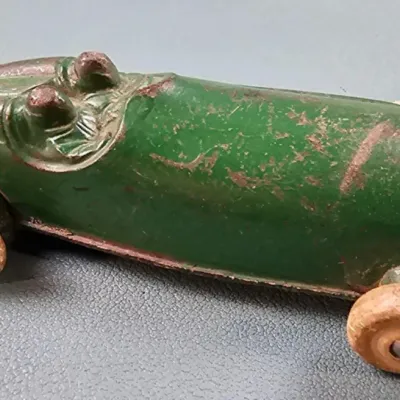 Vintage green cast iron bobsled toy with wooden wheels, showing significant paint wear and patina consistent with age.