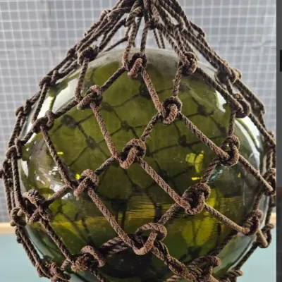 Vintage green glass Japanese fishing float encased in a hand-knotted brown rope net.