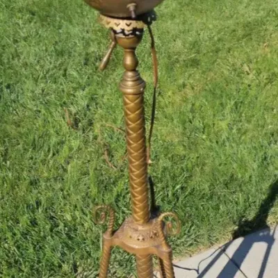 Antique brass banquet lamp stand with a tripod base, featuring ornate embossed details and a textured column, missing its glass shade and...