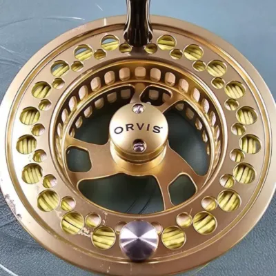 Orvis gold-anodized aluminum fly fishing reel, showing some light rim wear and spooled with yellow line.