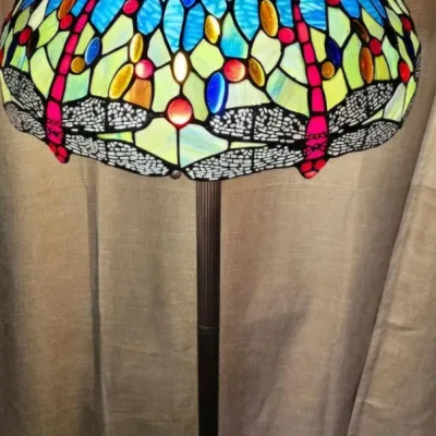 Tiffany-style dragonfly floor lamp featuring a vibrant stained glass shade with blue, green, and red accents on a dark metal base.