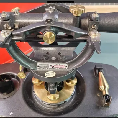 Vintage David White Instruments transit level with brass knobs and leveling base, showing minor wear from use.