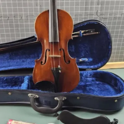 Vintage violin with a warm wood finish, complete with a blue velvet-lined hard case, bow, shoulder rest, extra bridge, strings, and rosin.