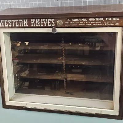 Vintage Western Knives wooden countertop display case with a glass front door, featuring original advertising graphics along the top header.