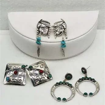 Sale Photo Thumbnail #49: Three pairs of Southwestern-style sterling silver earrings, including Native American face dangles with turquoise beads, square stamped studs with turquoise and coral accents, and turquoise-set naja hoop dangles.