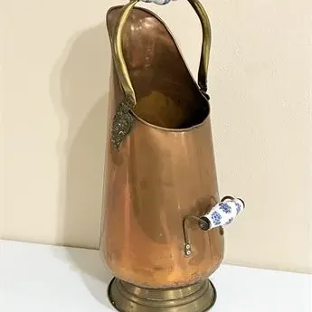 Sale Photo Thumbnail #36: Vintage copper and brass coal scuttle featuring blue and white ceramic handles and a pedestal base.