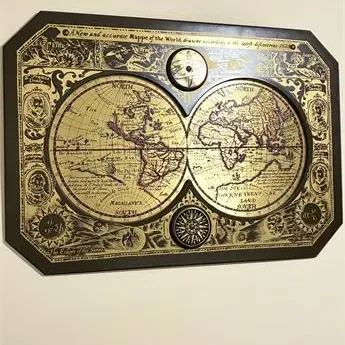 Sale Photo Thumbnail #24: Vintage gold foil world map plaque featuring a double hemisphere design with ornate borders, mounted on a dark wooden backing.