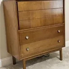 Sale Photo Thumbnail #8: Mid-century modern tallboy dresser in a warm wood finish, featuring three upper drawers with integrated pulls and two lower drawers with round metal knobs.