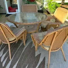 Sale Photo Thumbnail #24: Five-piece wicker patio dining set including a round glass-top table and four matching armchairs with beige cushions.