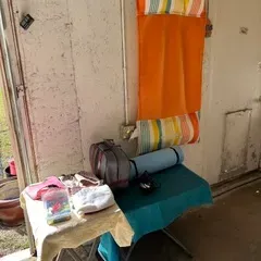 Vintage orange and striped folding beach mat hanging on a wall above a small table with a rolled yoga mat and other accessories.