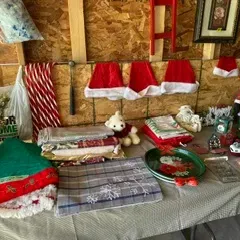 Assorted Christmas decorations and linens, including Santa hats, a tree skirt, holiday tablecloths, a plush polar bear, and a Santa...
