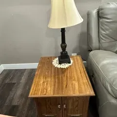 Sale Photo Thumbnail #54: Traditional oak end table with lower cabinet doors, paired with a dark-finished turned wood table lamp and cream fabric shade.