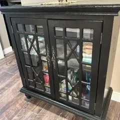 Sale Photo Thumbnail #62: Contemporary black-painted wooden accent cabinet featuring double glass doors with geometric fretwork overlays and metal hardware.