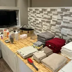 Sale Photo Thumbnail #61: Assorted bathroom linens, toiletries, and a small electronic scale displayed on a tiled bathtub deck.