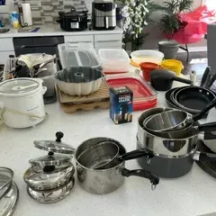 Sale Photo Thumbnail #42: Assorted kitchenware and small appliances, including stainless steel pots, a rice cooker, a bundt pan, and food storage containers, displayed on a kitchen island.