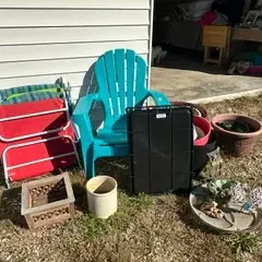 Assorted outdoor items including a turquoise plastic Adirondack chair, folding lawn chairs, various planters, and garden decor.