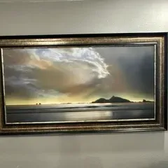 Sale Photo Thumbnail #55: Large panoramic landscape painting depicting a dramatic sunset over a coastal scene, housed in an ornate dark wood and gold-toned frame.