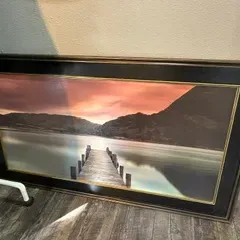 Sale Photo Thumbnail #45: Large framed landscape print depicting a wooden dock leading into a calm lake at sunset, housed in a wide dark wood frame with gold inner trim.