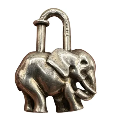Sale Photo Thumbnail #148: Hermès silver elephant padlock charm, featuring the brand name engraved on the shackle, showing light surface wear and patina.