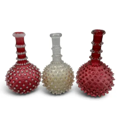 Sale Photo Thumbnail #41: Trio of vintage Fenton hobnail glass barber bottles, featuring one cranberry opalescent, one white opalescent, and one cranberry glass bottle.
