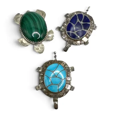 Sale Photo Thumbnail #107: Three vintage sterling silver turtle pendants featuring inlaid gemstones, including malachite, lapis lazuli, and turquoise.
