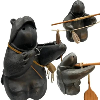 Sale Photo Thumbnail #78: Three views of a dark-glazed ceramic turtle figurine, depicting a turtle wearing a bear headdress and holding a wooden paddle and spear with feather accents.