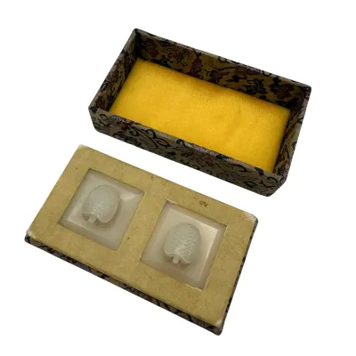 Sale Photo Thumbnail #74: Pair of Chinese carved white jade turtle figurines, presented in a traditional fabric-covered display box with a yellow padded interior.