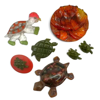 Sale Photo Thumbnail #99: Collection of vintage celluloid and bakelite turtle brooches and pins, featuring various colors and styles.
