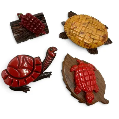 Sale Photo Thumbnail #100: Four vintage carved Bakelite and wood turtle brooches, featuring various red and yellow carved shells on wooden bases.
