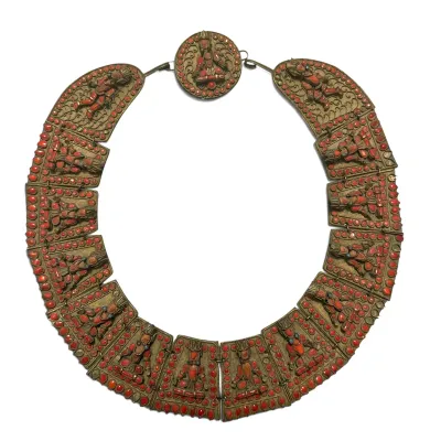 Sale Photo Thumbnail #108: Antique Tibetan or Nepalese brass collar necklace featuring hinged panels with filigree work, coral cabochons, and central deity figures.