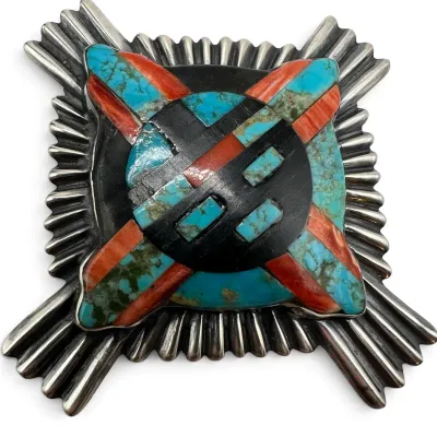 Sale Photo Thumbnail #143: Vintage Native American sterling silver pin featuring a Sunface design inlaid with turquoise, spiny oyster shell, and jet, set against a ribbed silver border.