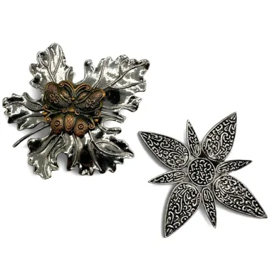 Sale Photo Thumbnail #105: Two vintage silver-tone brooches, including a leaf design with a copper-tone butterfly accent and a stylized floral design with intricate textured detailing.