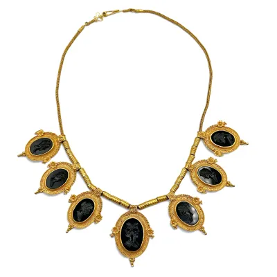 Sale Photo Thumbnail #153: Antique Etruscan Revival gold necklace featuring seven oval black glass intaglio drops depicting classical figures, set in ornate filigree frames.