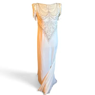 Sale Photo Thumbnail #176: Bob Mackie Vintage 1920s-style ivory silk chiffon gown featuring intricate silver beadwork and sequin embellishments with a fringed hemline.