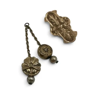 Sale Photo Thumbnail #104: Antique Victorian gold-filled collar pin and matching chatelaine-style dangle pin set, featuring ornate floral and starburst engravings accented with seed pearls.