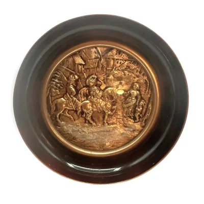 Sale Photo Thumbnail #81: Vintage embossed copper wall plaque featuring a detailed relief scene of figures on horseback in a village setting, mounted in a dark circular frame.