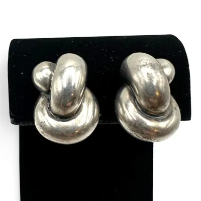 Sale Photo Thumbnail #129: Vintage sterling silver clip-on earrings featuring a chunky, interlocking knot design with a polished finish and light patina.
