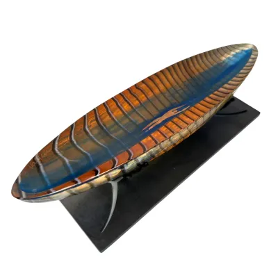 Sale Photo Thumbnail #37: Contemporary art glass canoe sculpture featuring intricate murrine patterns in amber and blue, displayed on a custom metal stand.