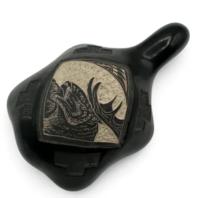 Sale Photo Thumbnail #76: Southwestern-style blackware pottery pipe featuring a carved sgraffito design of a howling wolf or coyote against a textured background.