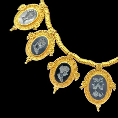 Sale Photo Thumbnail #154: Antique gold fringe necklace featuring four oval intaglio pendants depicting classical profile portraits, set in ornate filigree frames.