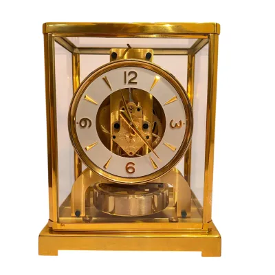 Sale Photo Thumbnail #98: Vintage Jaeger-LeCoultre Atmos clock featuring a brass and glass case, a white dial with gold-tone markers, and a visible perpetual motion mechanism.