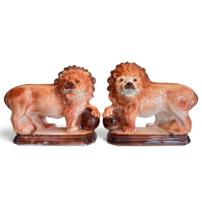 Sale Photo Thumbnail #3: Pair of vintage Staffordshire-style glazed ceramic lion figurines, each resting a paw on a ball atop a rectangular plinth base.