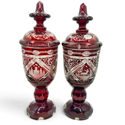 Sale Photo Thumbnail #50: Pair of Bohemian ruby red cut-to-clear glass lidded chalices, featuring intricate etched forest scenes with a stag and castle, on faceted pedestal bases.