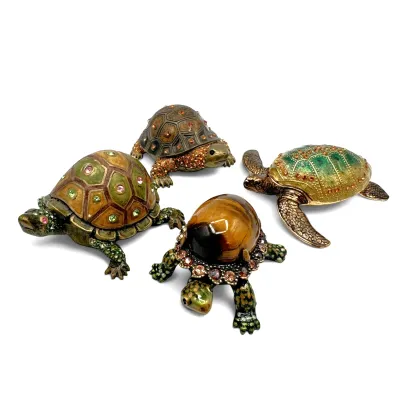 Sale Photo Thumbnail #83: Collection of four jeweled and enameled metal turtle trinket boxes, featuring rhinestone accents and one with a tiger's eye style shell.