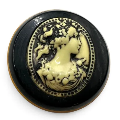 Sale Photo Thumbnail #101: Vintage round cameo brooch featuring a cream-colored female profile in relief on a black background.