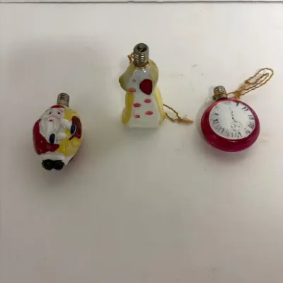 Sale Photo Thumbnail #7: Three vintage Christmas light bulb style ornaments, featuring a Santa Claus, a spotted dog, and a pocket watch design, showing some paint wear consistent with age.