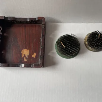 Sale Photo Thumbnail #14: Vintage carved wooden display stand with some surface wear, shown alongside two metal flower frog pin holders.