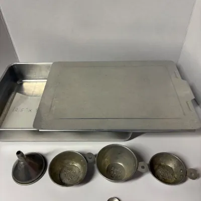Sale Photo Thumbnail #60: Vintage aluminum baking pan with sliding lid, measuring 12.5 by 9 inches, accompanied by a small metal funnel, three vintage measuring cups.