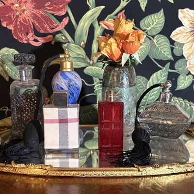 A Collection of Decorative Perfume Bottles and Vanity Items on Mirrored Tray